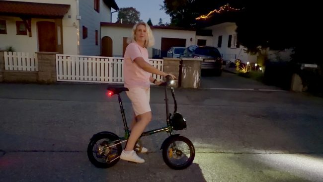 Engwe Zip Falt-E-Bike in der Dämmerung – Person steht entspannt daneben