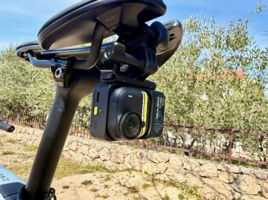 Rennrad mit montierter Insta360 Go Ultra am Straßenrand, Meer und Berge im Hintergrund