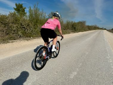 Rennradfahrerin in pinkfarbenem Trikot fährt schnell auf Asphaltstraße, aufgenommen mit Insta360 Go Ultra