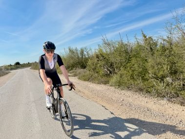 Rennradfahrer in schwarzem Outfit fährt auf Küstenstraße, Seitenansicht – aufgenommen mit Insta360 Go Ultra