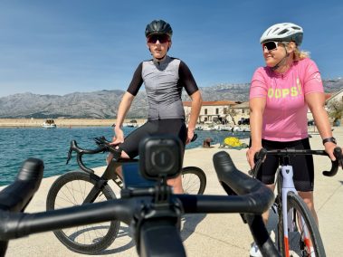 Zwei Rennradfahrer mit ihren Rädern am Mittelmeerhafen, einer trägt die Insta360 Go Ultra am Körper