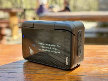 Insta360 Go Ultra Action Pod auf Tisch zeigt KI-Assistenten Kira auf dem Bildschirm – Firmware 1.8.60