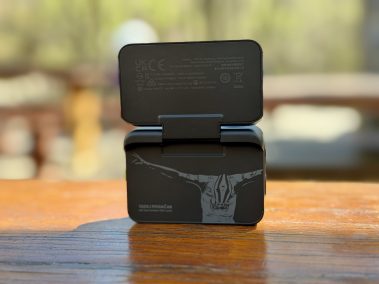 Insta360 Go Ultra mit aufgeklapptem Action Pod auf Holztisch, 2,5-Zoll-Touchscreen sichtbar