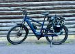 MapFour Roam blau mit Seitentasche vor rustikaler Holzwand – Touring Setup