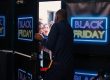 Kunden drängen zur Black-Friday-Aktion in ein Geschäft mit Neonschild