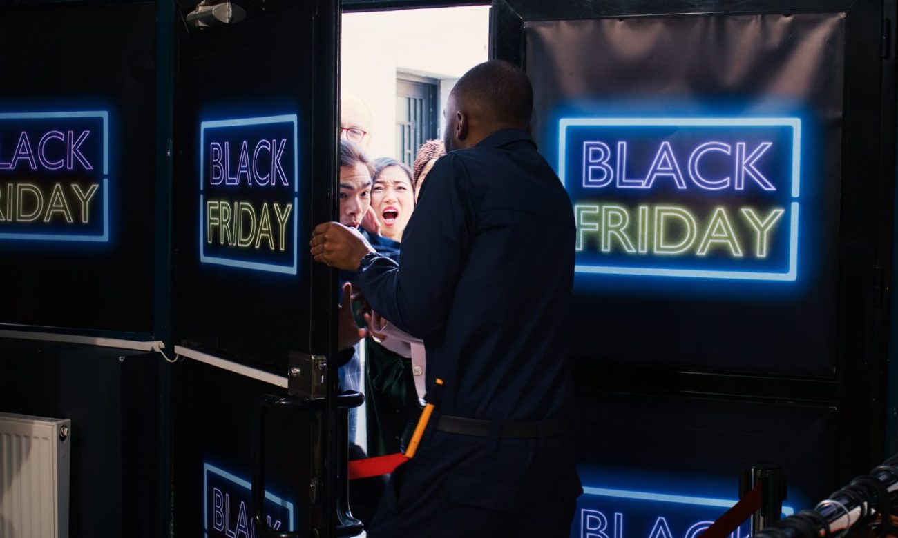 Kunden drängen zur Black-Friday-Aktion in ein Geschäft mit Neonschild